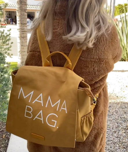 butterscotch color bag that has a mama bag print with a women carrying the bag with blonde hair