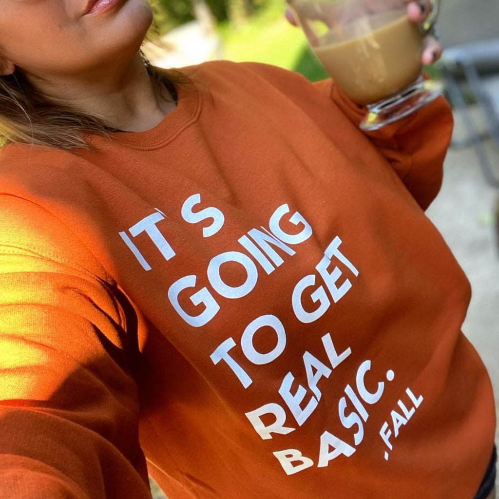 image of pumpkin color sweatshirt, woman wearing fall sweatshirt pullover holding a cup of coffee, probably pumpkin spice latte, in a glass mug