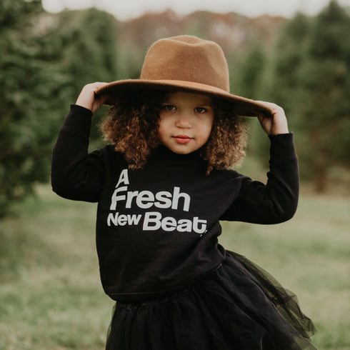 little girl posing in graphic sweatshirt that says a fresh new beat
