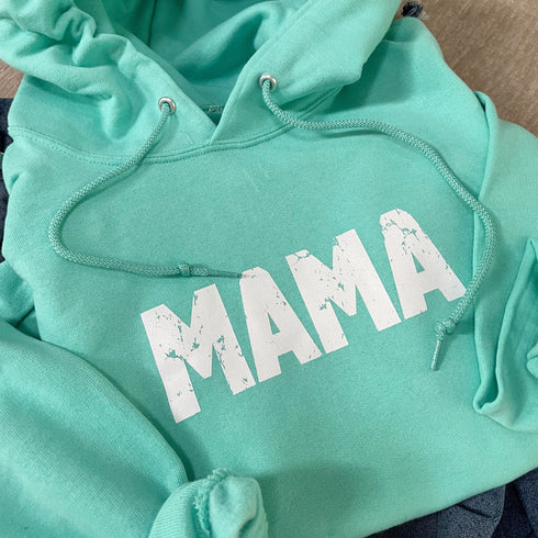 closeup of a flat lay of hoodie ocean blue color with a distressed mama screen print design cute and cozy hoodie for women or mothers