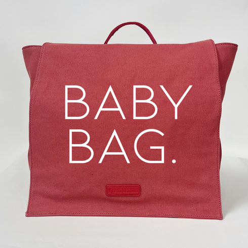 coral color backpack made with durable canvas and a vegan leather handle with screen print text that says baby bag