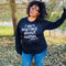 black woman in glasses and red lipstick wearing black soft pullover sweatshirt bella and canvas with screen print design saying i aint worried about nothin referencing jeremiah 2911 bible verse