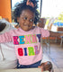 little girl wearing a pink sweatshirt with custom letter patches, chenille patches with her nick name that says kenny girl, this is custom shirt with multi color letter patches available in toddler sizes, youth sizes, and adult sizes