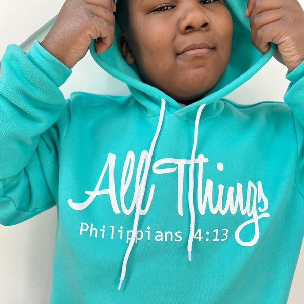 teen wearing inspring hoodie in teal color that is referencing scripture in the bible Philippians 4:13 I can do all things through christ who strengthens me.