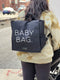 mom carrying black backpack used for a diaper bag to carry all baby items and change of clothes, the screen print on the bag says baby bag design