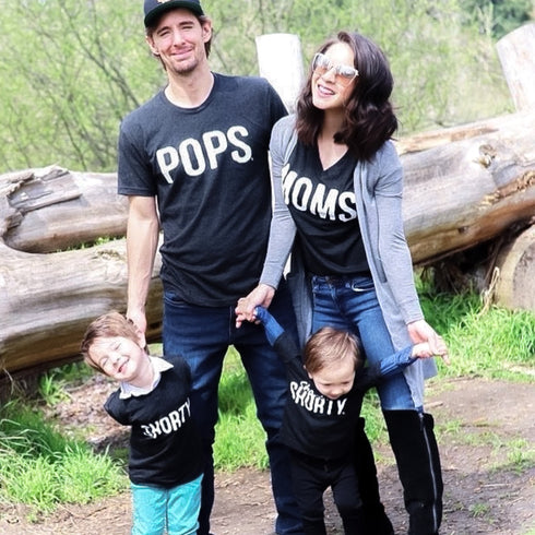 mom dad and two sons matching at an advenuture park like the zoo or family vacation in black shirts that say moms, pops shorty shirts